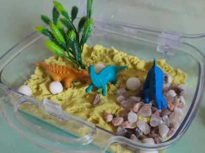 Maletinha transparente com área, pedrinhas, bichinhos de plástico e vegetação para lembrancinha customizada sensorial